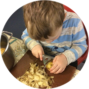 One of the Little Acorns Nursery children peeling potatoes for January's Recipe of the Month.